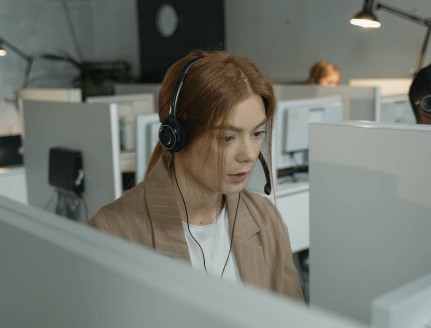 female Customer Support Representative wearing her headset while looking at the computer on her workstation