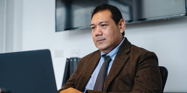 Data Manager sitting on his desk and looking at his laptop screen