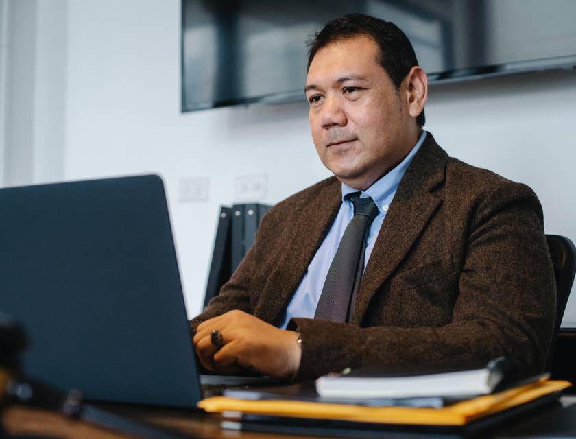 Data Manager sitting on his desk and looking at his laptop screen