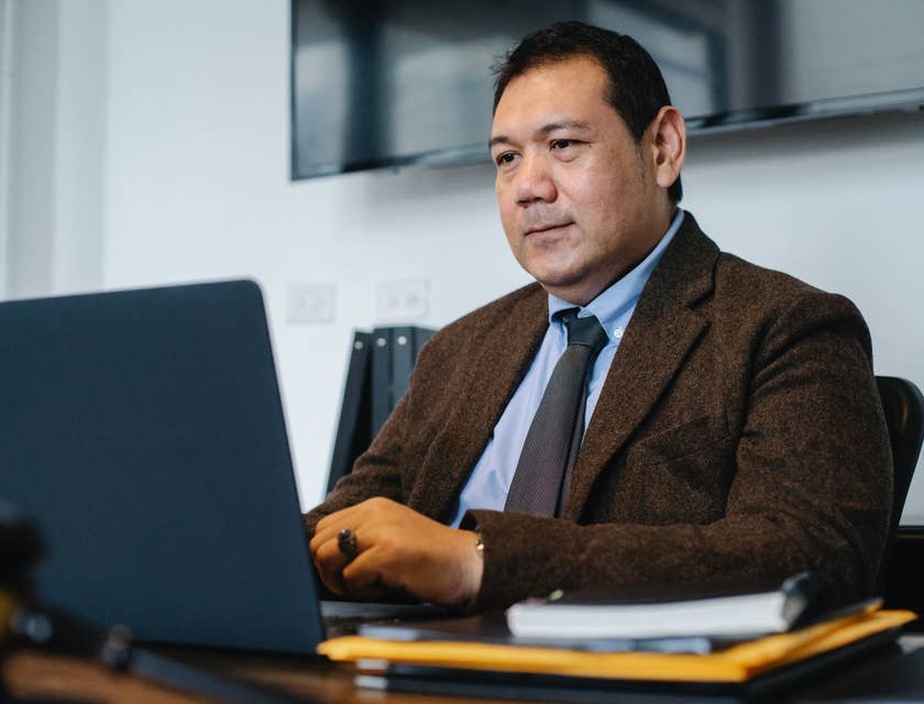 Data Manager sitting on his desk and looking at his laptop screen