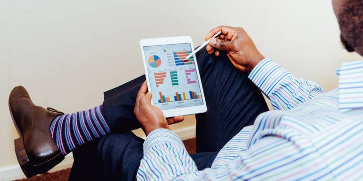 Data Quality Analyst holding a tablet and looking at the details of a data analytics report