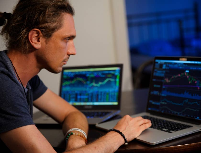 Data Scientist working on graph reports of raw data on two laptop screens for interpretation