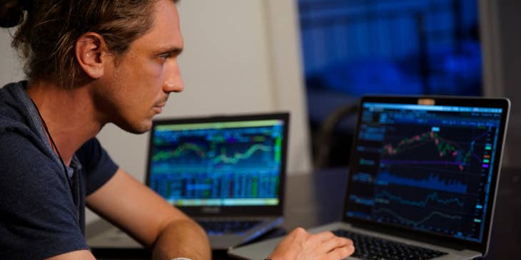 Data Scientist working on graph reports of raw data on two laptop screens for interpretation