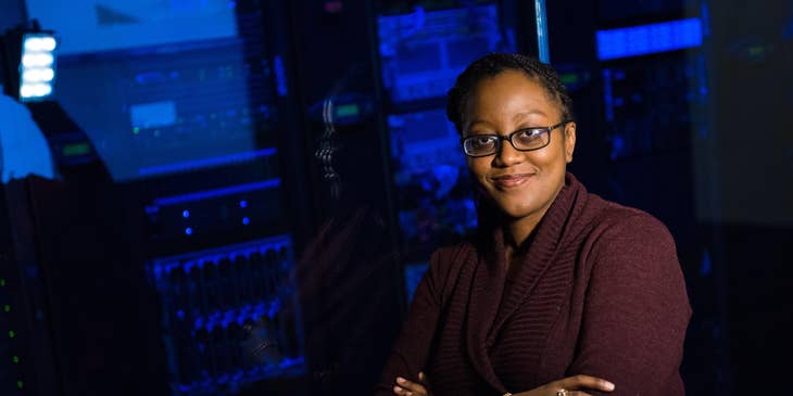A database administrator wearing glasses and standing outside the server room.