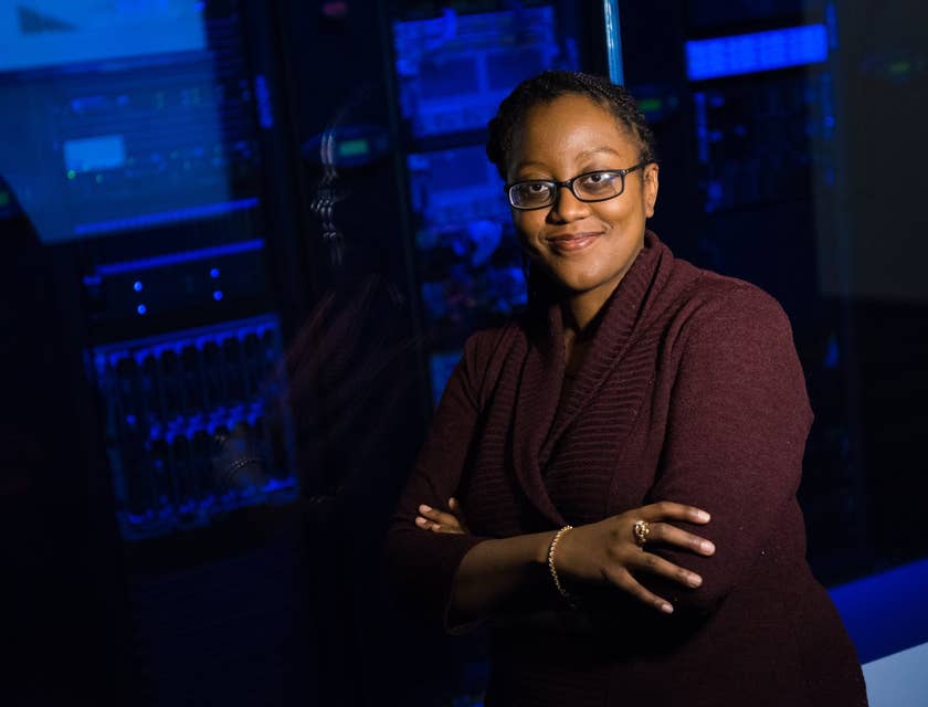 A database administrator wearing glasses and standing outside the server room.