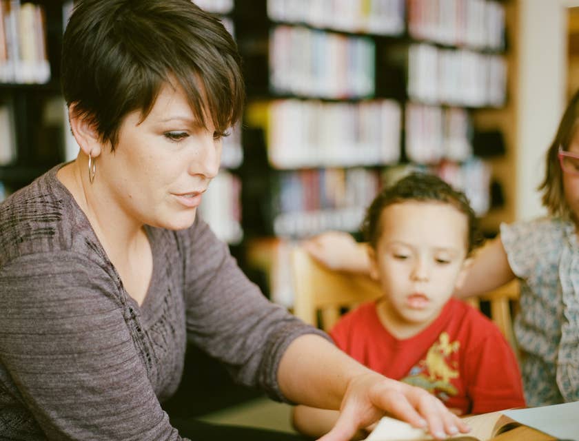 Daycare Worker turning a page on a book while the children looks on