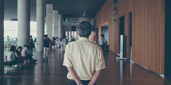 Dean of Students watching a group of students in the hallway while holding a piece of paper