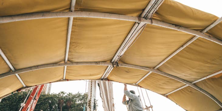 Deckhand adjusting sails on a boat