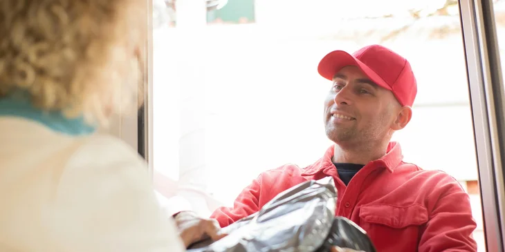 A delivery boy handing a package to a female client.