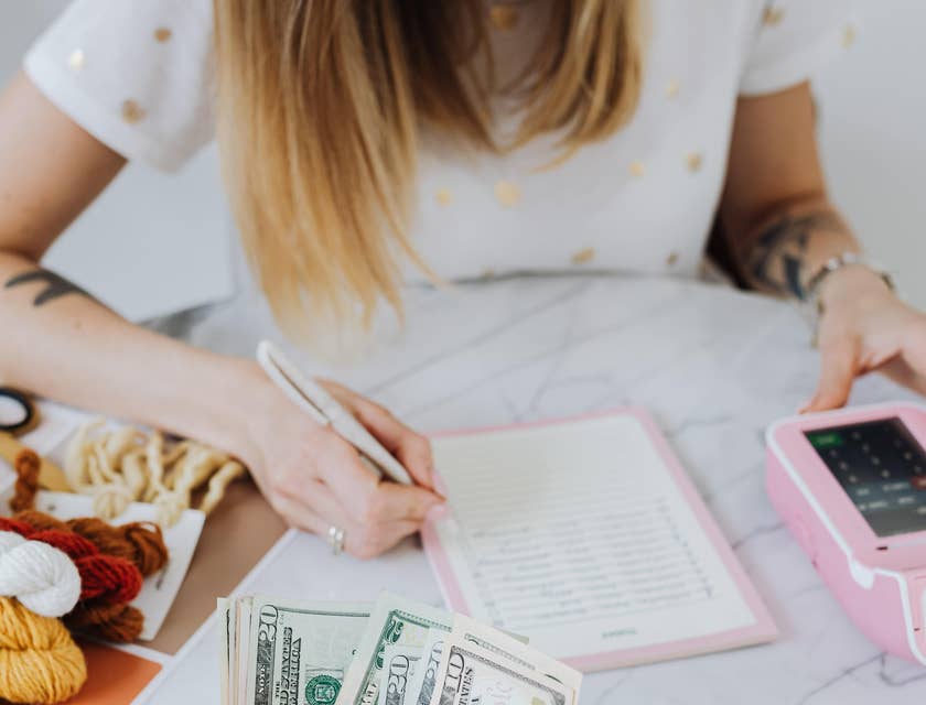 A Female Dental Insurance Coordinator processing a payment and writing notes on a notebook.