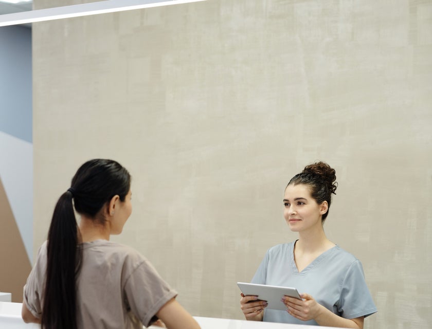 Dental Receptionist greeting and assisting patients to fill out information forms.