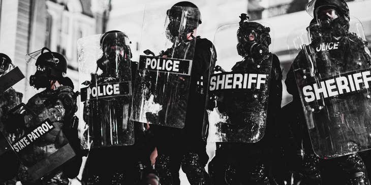 Deputy Sheriff wearing full protective gear and shield while on-duty at a high alert area with the rest of the team