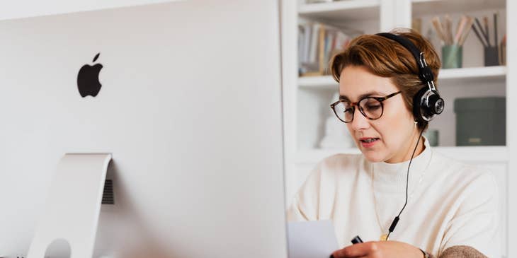 Desktop Support Engineer sitting at her workstation while holding a paper and explaining the details of the program to the client over the phone