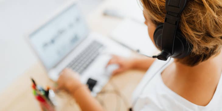 Desktop Support Technician wearing a headset while assisting a client over the phone and looking at her laptop