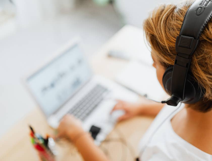 Desktop Support Technician wearing a headset while assisting a client over the phone and looking at her laptop