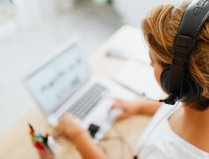 Desktop Support Technician wearing a headset while assisting a client over the phone and looking at her laptop