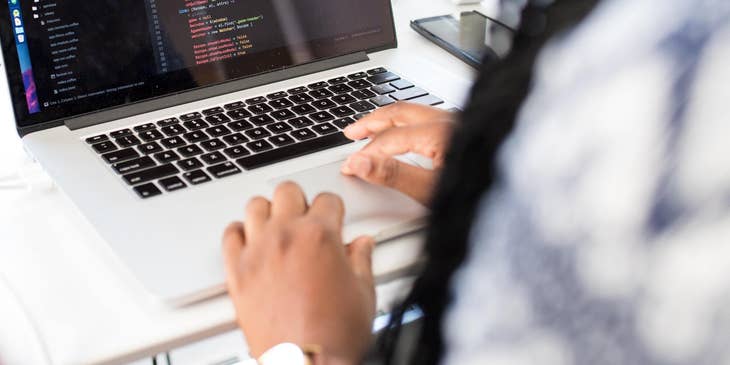 Woman typing on computer creating a Devops Architect resume.