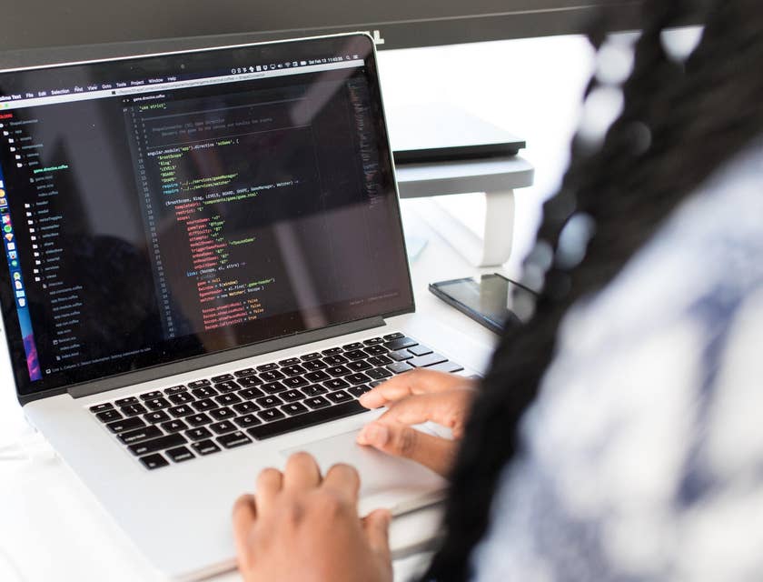 Woman typing on computer creating a Devops Architect resume.