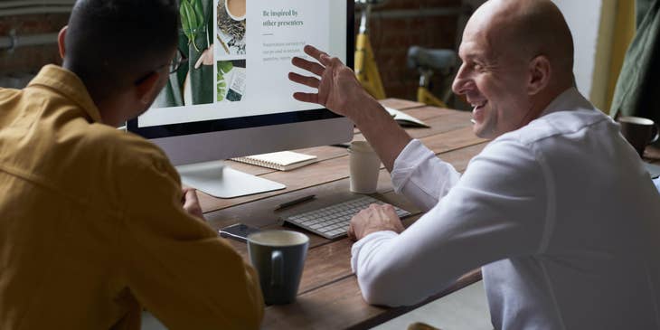 young Digital Designer presenting his final product with his client while he gives him feedback regarding the design