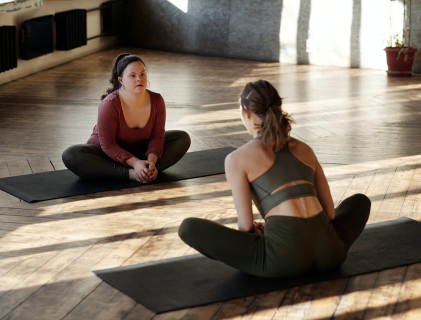 Direct Support Professional sitting on the floor doing yoga with her client