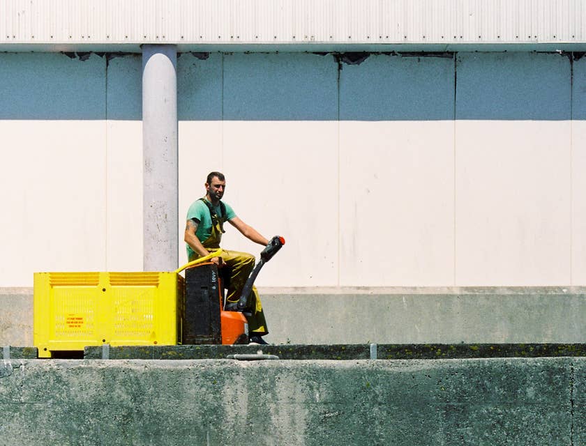 A Dock Worker driving a small equipment on the side of the docks on his way to fetch cargos.