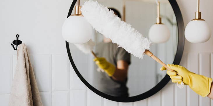 Domestic Helper dusting a lighting fixture