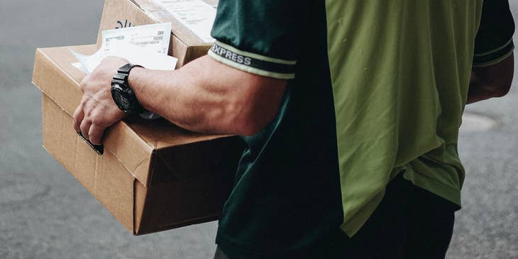 A Driver Helper carrying packages on his way to load them into the delivery vehicle.