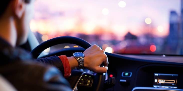A Driver driving around the city about to pick up a client from a hotel.