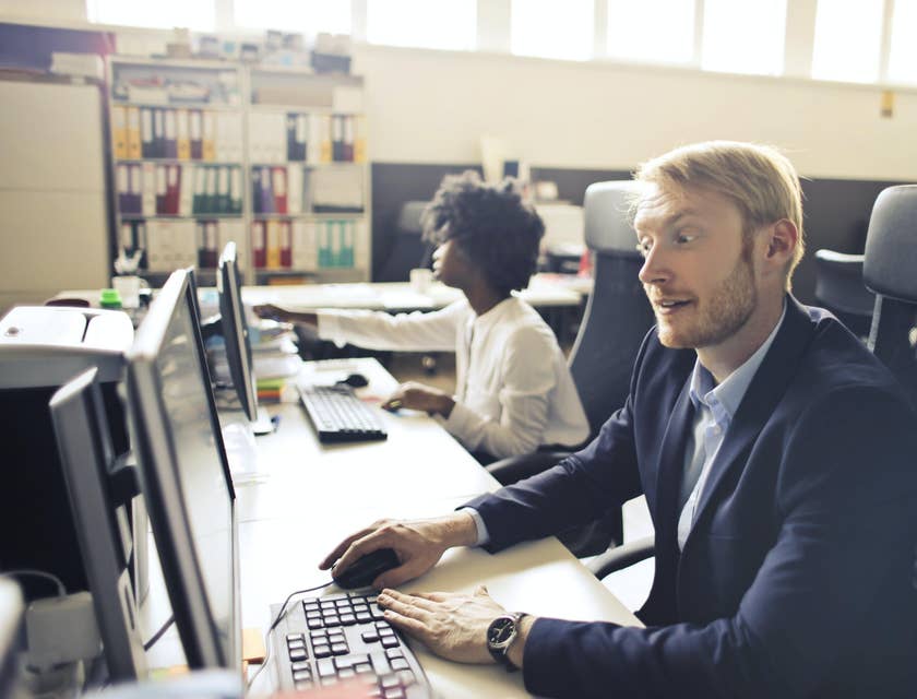 A Duty Manager on a computer working beside his employee.