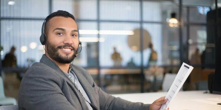 A man sitting at a desk holding a document.