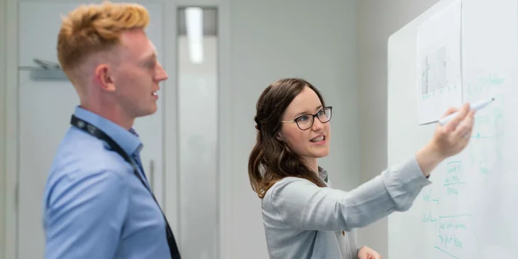An electrical drafter listening to a female engineer.