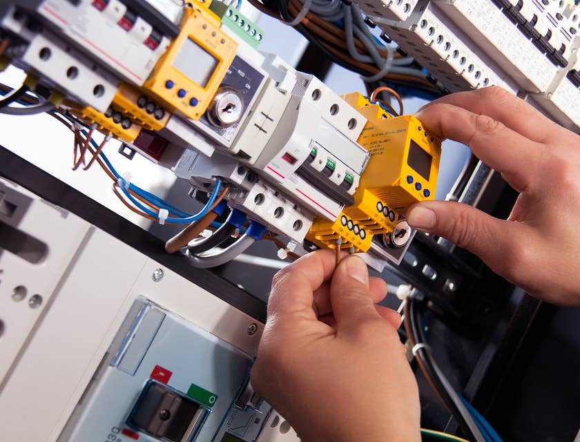Electrical Technician fixing cable wires in a panel board