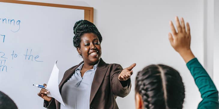 Elementary school teacher calls out a student to answer questions written on the board