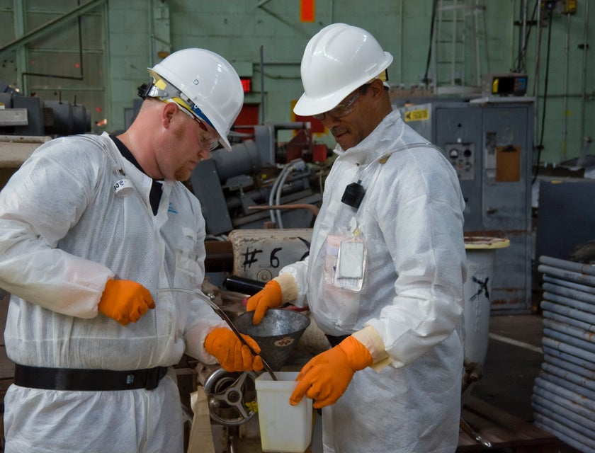 Engineering Technician transferring fluid samples into the bin being held by the Chief Engineer
