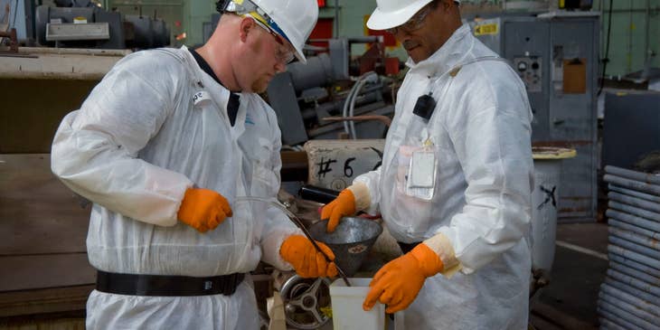 Engineering Technician transferring fluid samples into the bin being held by the Chief Engineer