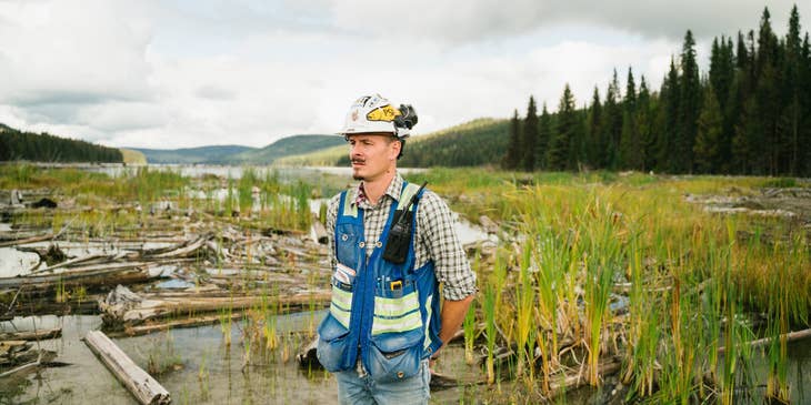 An environmental engineer with a hard hat and vest working at an engineering site.