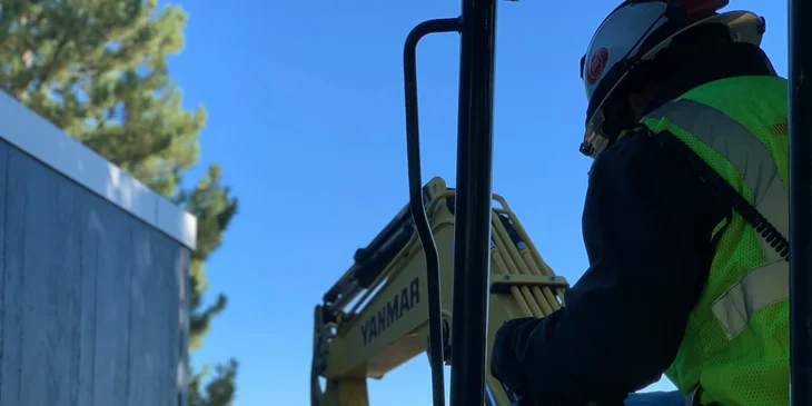 An equipment operator ensures safety while operating an excavator.