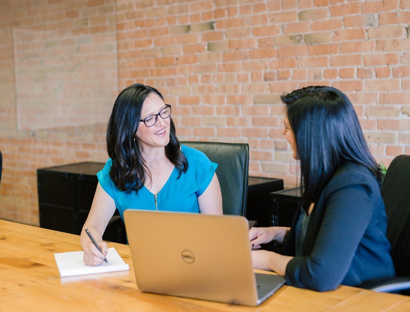 Equity Analyst sitting on the table with an open laptop while discussing details with her client inside the office