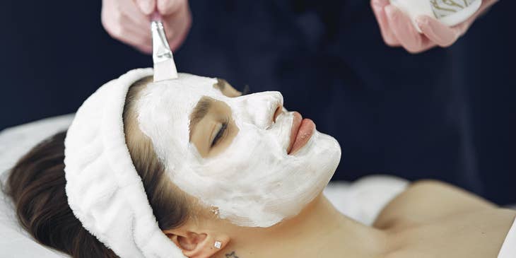 Esthetician applying the facial mask to the client.