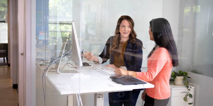 A Female Field Operations Manager in an office setting discussing with a colleague.