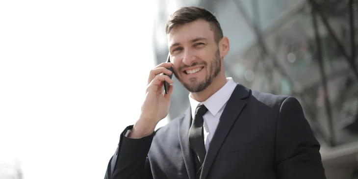 A financial officer wearing a black business suit while holding a mobile phone.