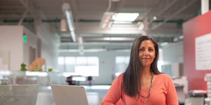 female Financial Specialist standing next to her open laptop