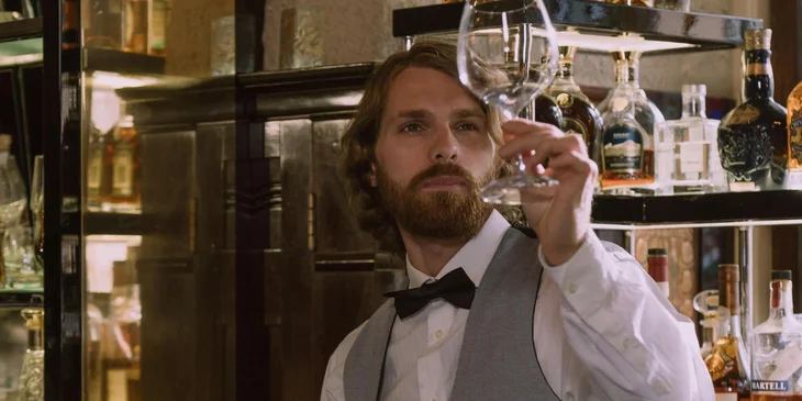 A floor staff ensuring the wine glass is clean.