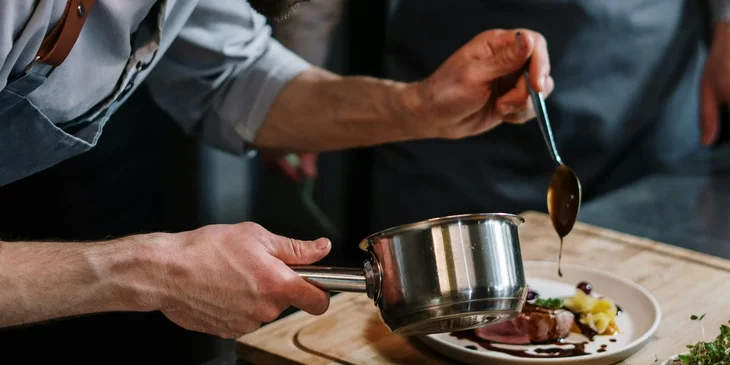 A food expeditor performing the finishing touches to a completed dish.