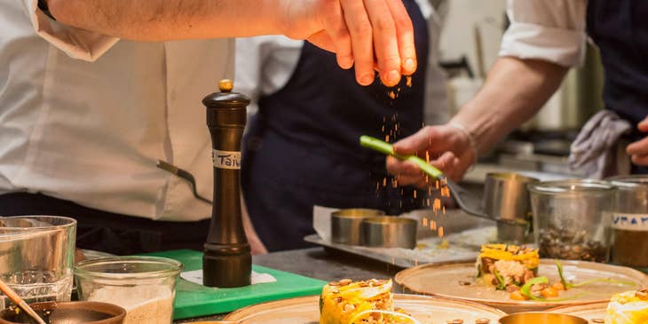 Food expeditor performing the finishing touches to completed dishes.
