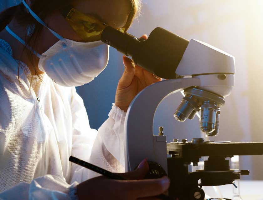 A Female Forensic Scientist in a laboratory interpreting evidence collected from a crime scene through a microscope.