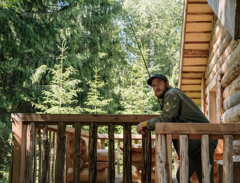 Forest Ranger leaning from the railings of the log cabin in the middle of the forest