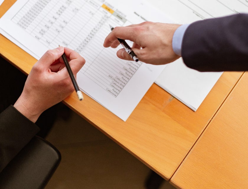 A Fraud Investigator working with a team member cross referencing documents to determine legitimacy of a fraud claim allegation.