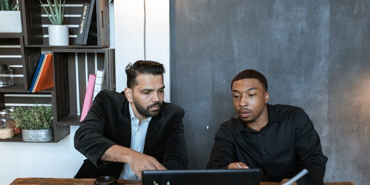 Two colleagues working on a laptop and discussing work.