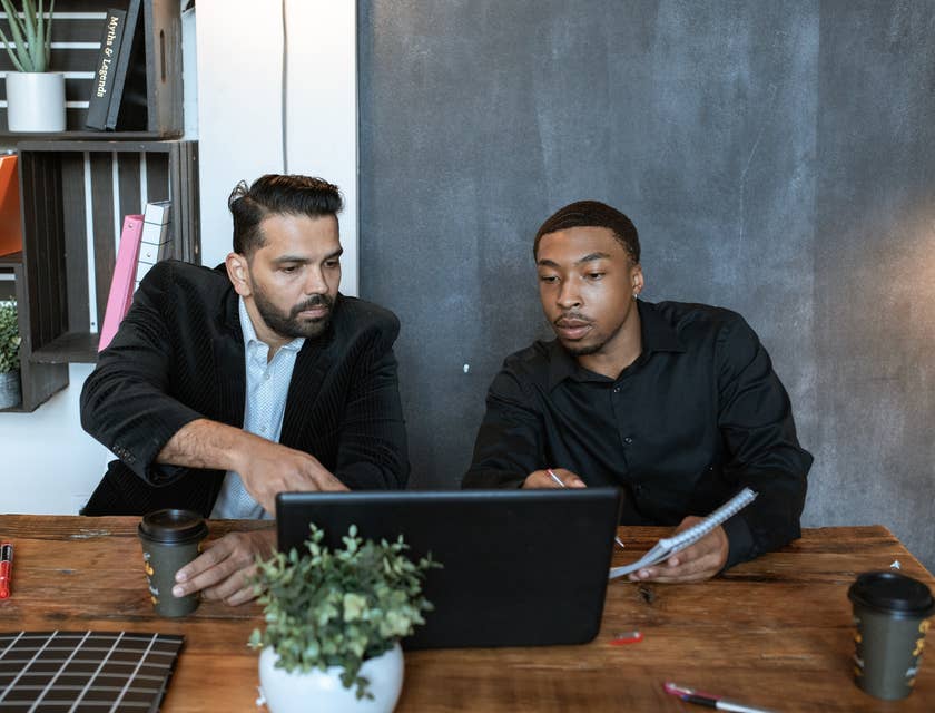 Two colleagues working on a laptop and discussing work.